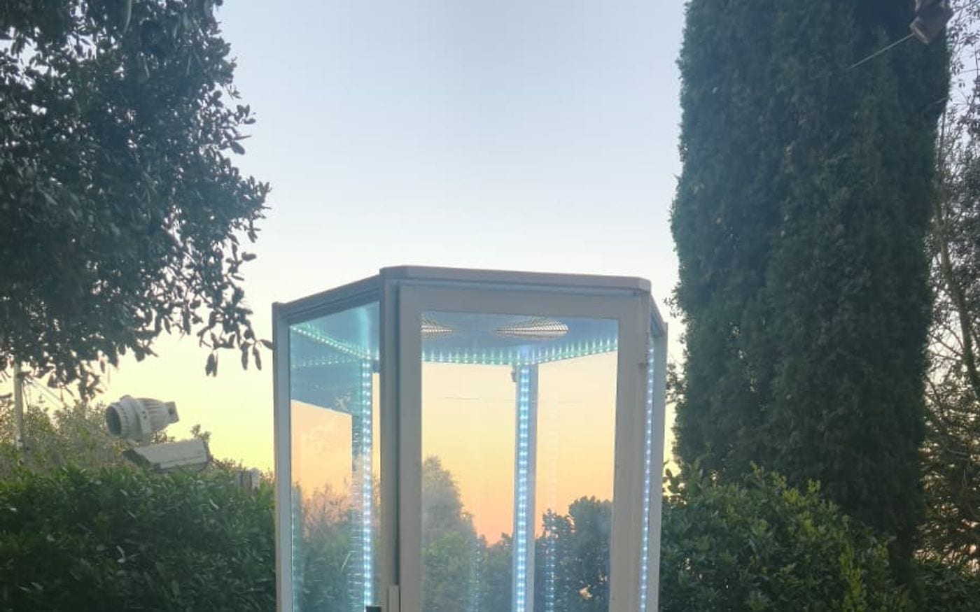 Cabina de viento con las tiras LED encendidas en un jardín al atardecer