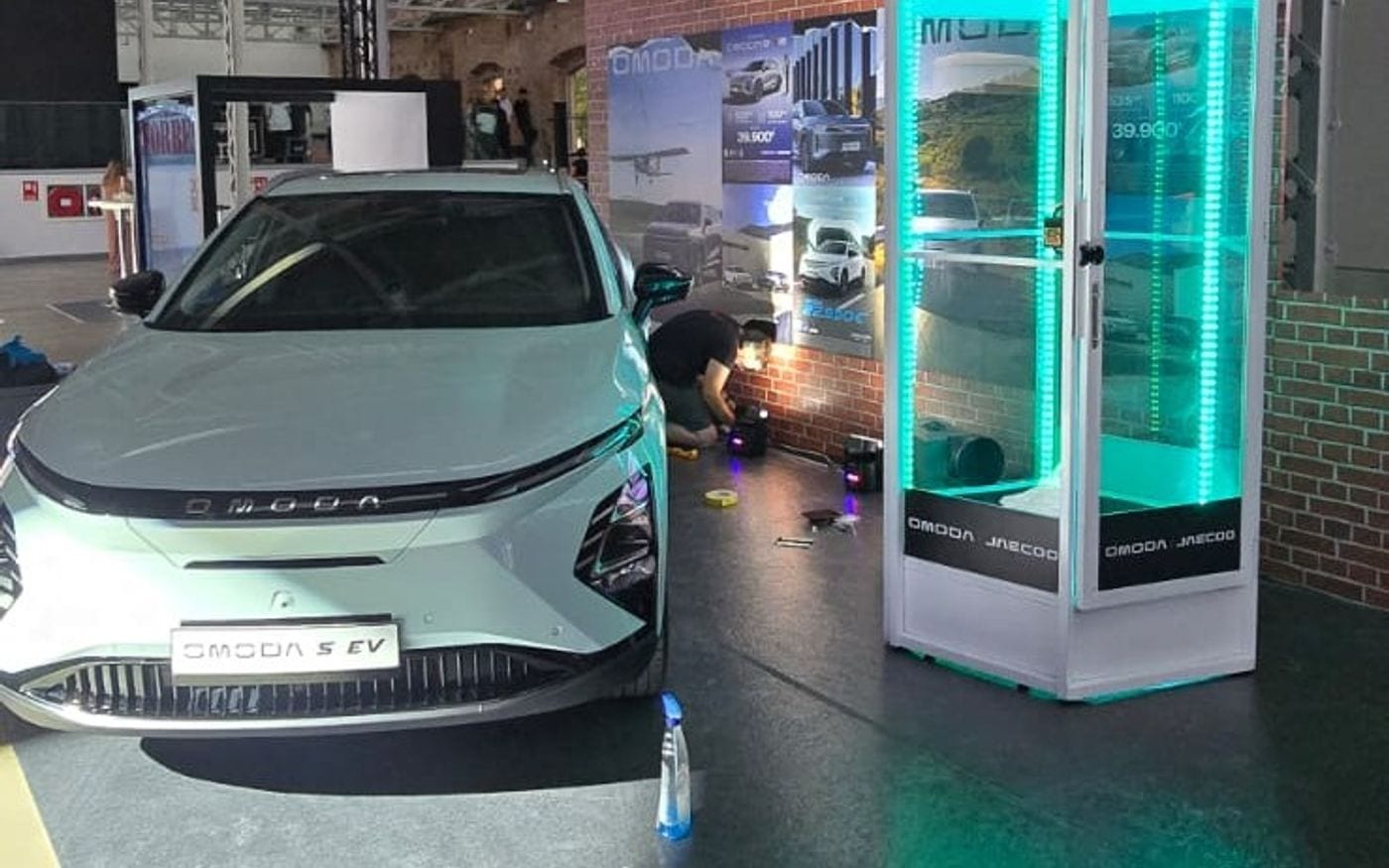 Cabina de viento con las tiras LED en verde agua junto a un coche eléctrico en una presentación