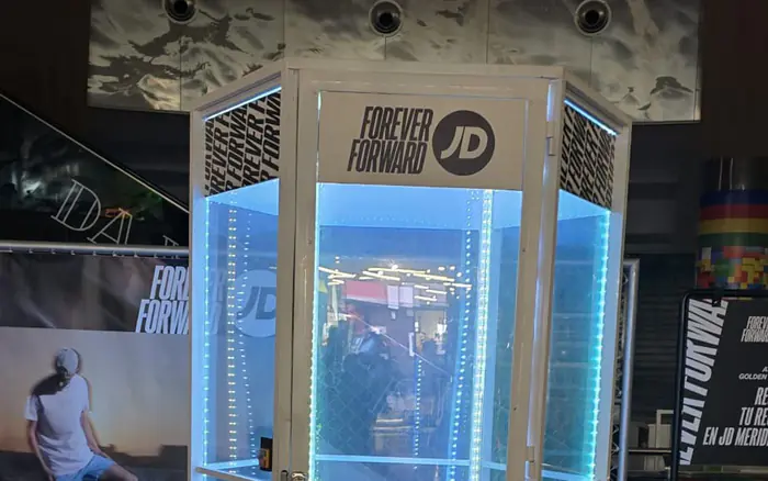 Cabina de viento con iluminación azul montada dentro de una tienda de ropa deportiva